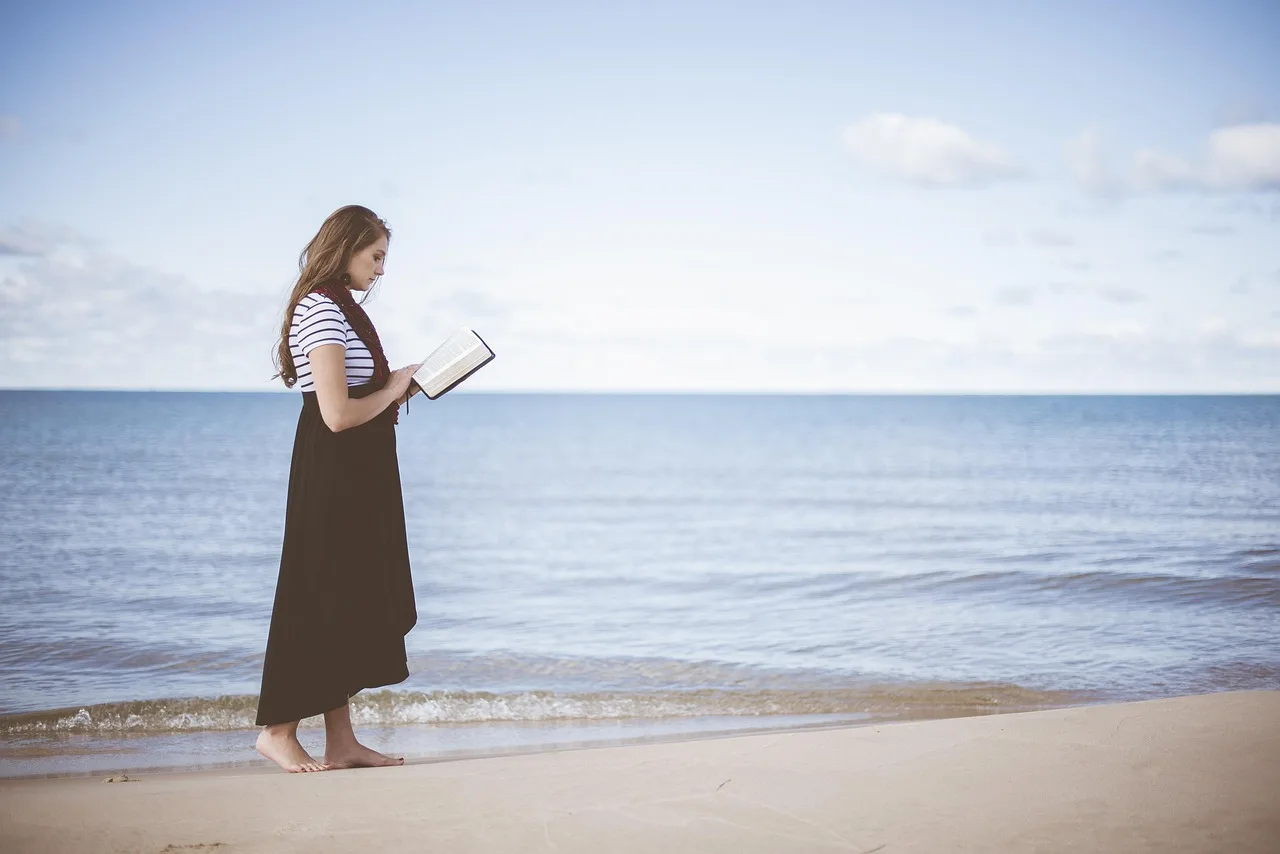 Woman reading on a beach, representing healing from religious trauma