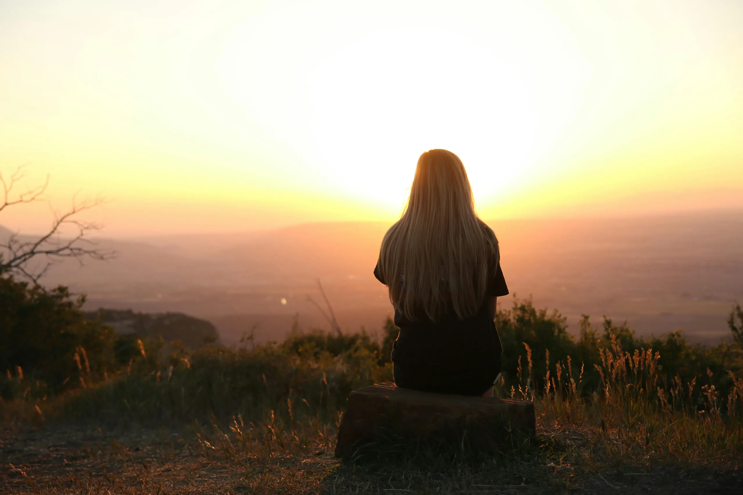Woman sitting alone in nature, reflecting on setting boundaries with parents