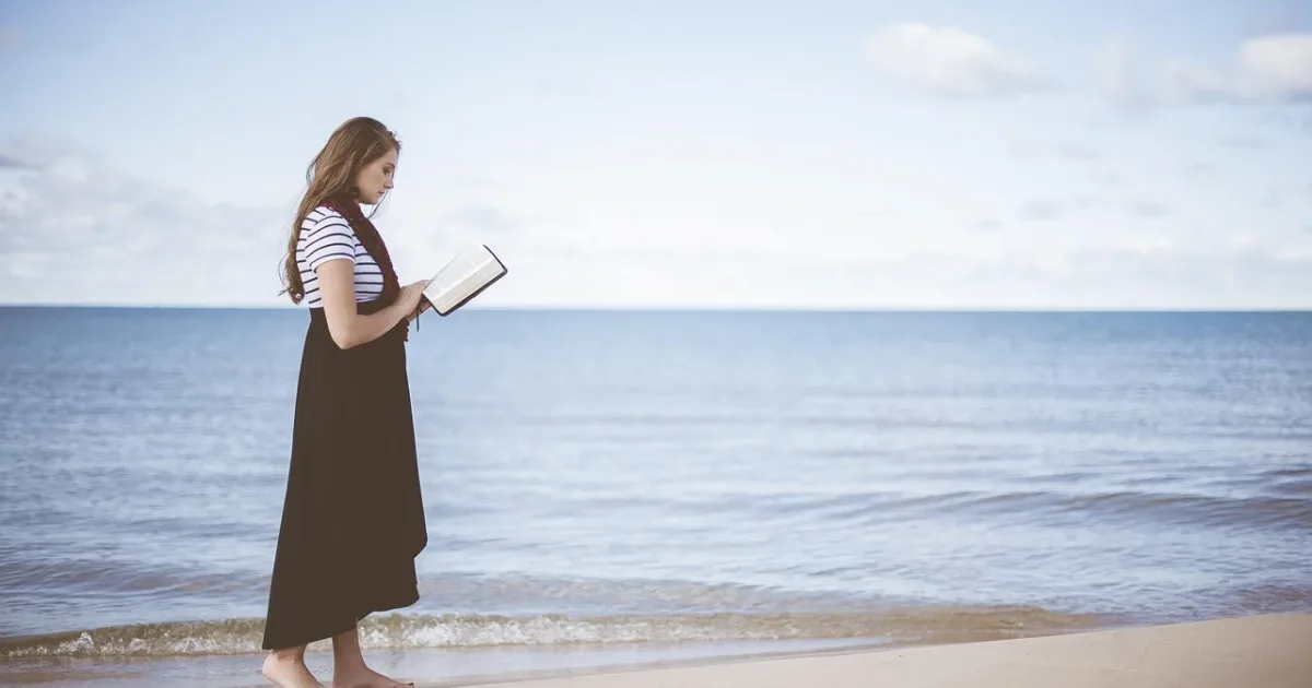 Woman reading on a beach, representing healing from religious trauma