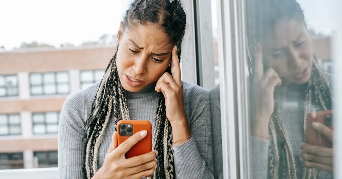 Unhappy woman looking at smartphone reflecting on the harmful relationship with her parents